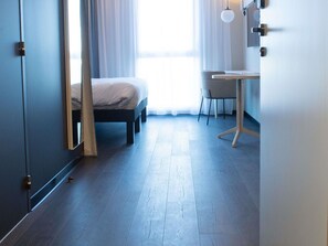 A room with a bed, a desk, and a chair.