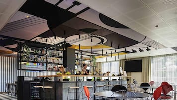 A bar area with stools, a counter, and shelves stocked with bottles.