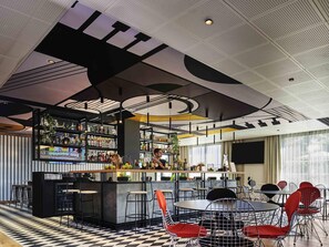 Un espace bar avec des tabourets, un comptoir et des étagères remplies de bouteilles.