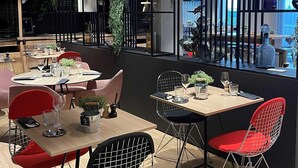 Un intérieur de restaurant moderne, avec des tables, des chaises et des plantes décoratives.