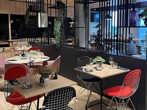 Een modern restaurantinterieur met tafels, stoelen en decoratieve planten.
