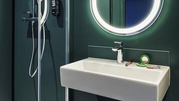 A bathroom with a white sink, a mirror, and a shower.