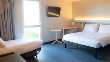 A hotel room with two beds, a desk, a chair, and a TV.