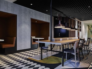 Een modern interieur met een geruit vloertje, zithoeken en hanglampen.