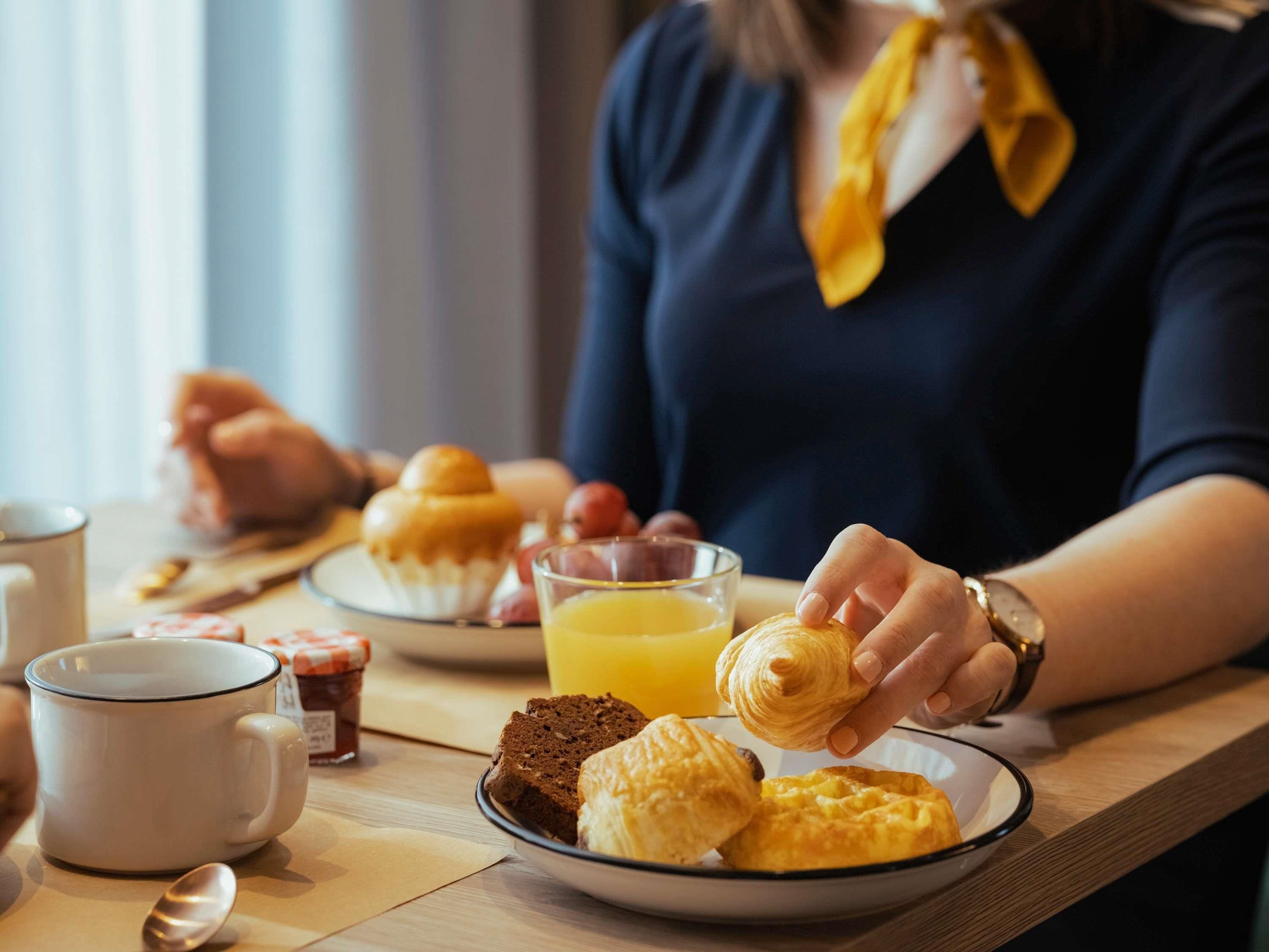Ein Frühstückstisch mit Gebäck, Orangensaft und einer Tasse.