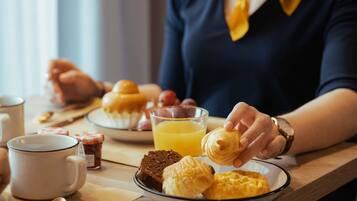 Ein Frühstückstisch mit Gebäck, Orangensaft und einer Tasse.