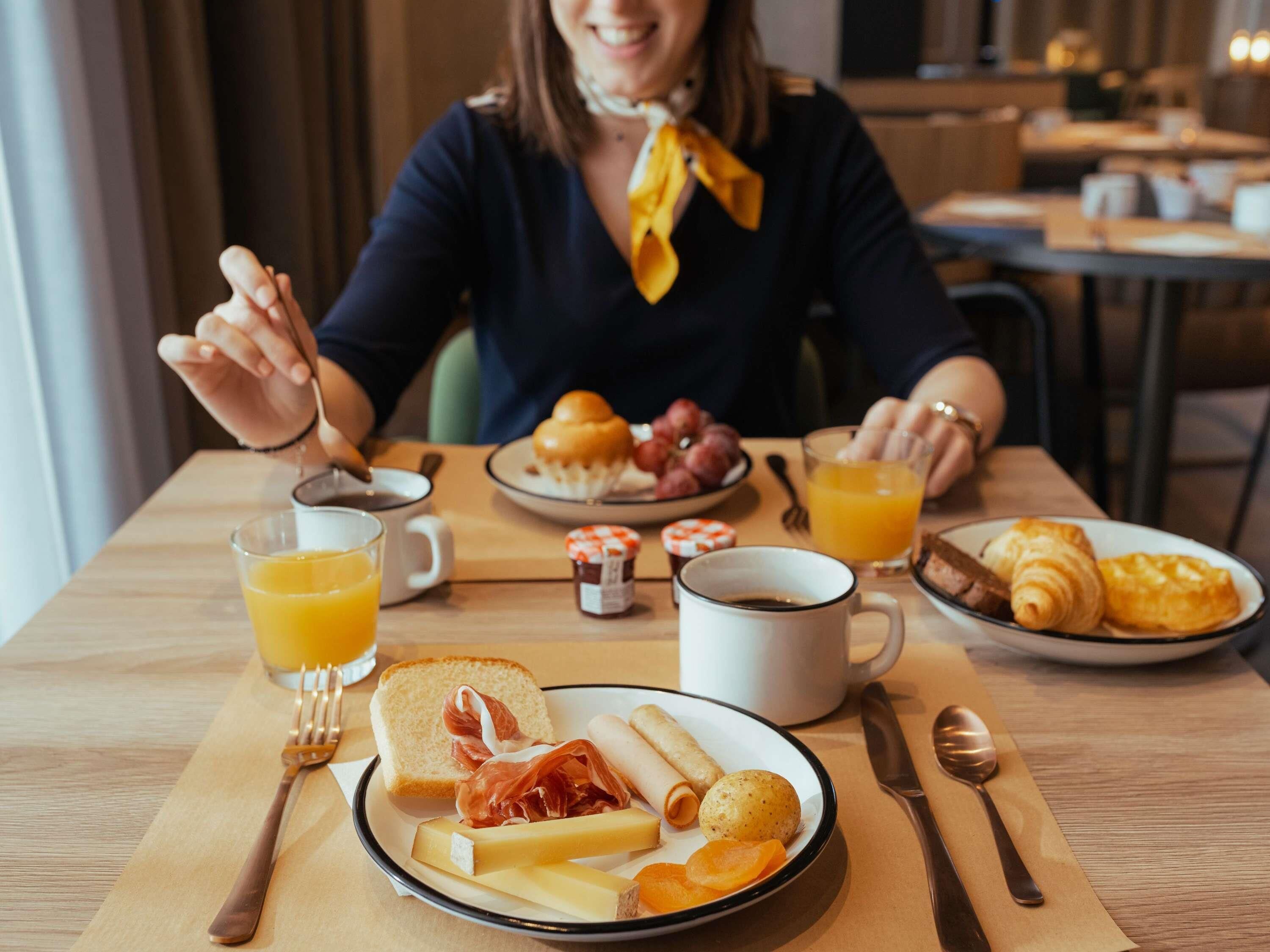 A breakfast setting with a plate of food, a glass of orange juice, and a coffee cup.