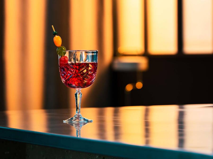 A cocktail glass with a decorative garnish on a reflective surface.