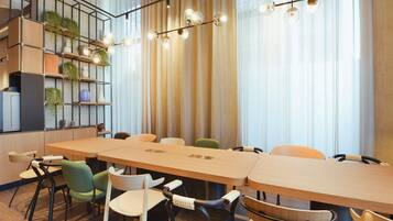 Une salle de réunion moderne, dotée d’une longue table, de nombreuses chaises et d’un luminaire au plafond.