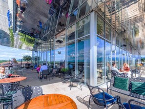 Un espace extérieur aménagé avec des tables et des chaises, de grandes baies vitrées et une vue sur le paysage.