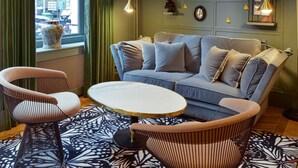 Una sala de estar moderna con un sofá azul, dos sillones, una mesa redonda de centro y alfombras estampadas.