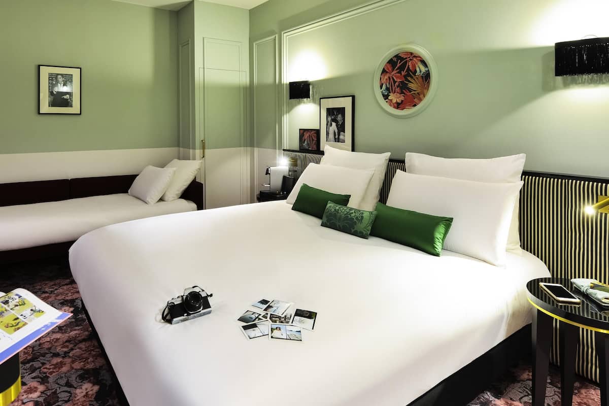 A hotel room with a large bed, two bedside tables, a sofa, and a mirror.