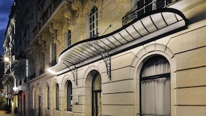 Un edificio histórico con ventanas arqueadas y un toldo curvo, probablemente un hotel.