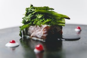 A dish with a piece of meat and green vegetables on a dark plate. - Garrya Nijo Castle Kyoto (Kyoto)