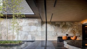 A modern interior with a stone wall, a reflective floor, and a seating area with a table and chairs. - Garrya Nijo Castle Kyoto (Kyoto)
