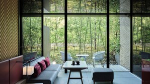 A modern room with a large window, a sofa, a table, and two chairs. - Garrya Nijo Castle Kyoto (Kyoto)