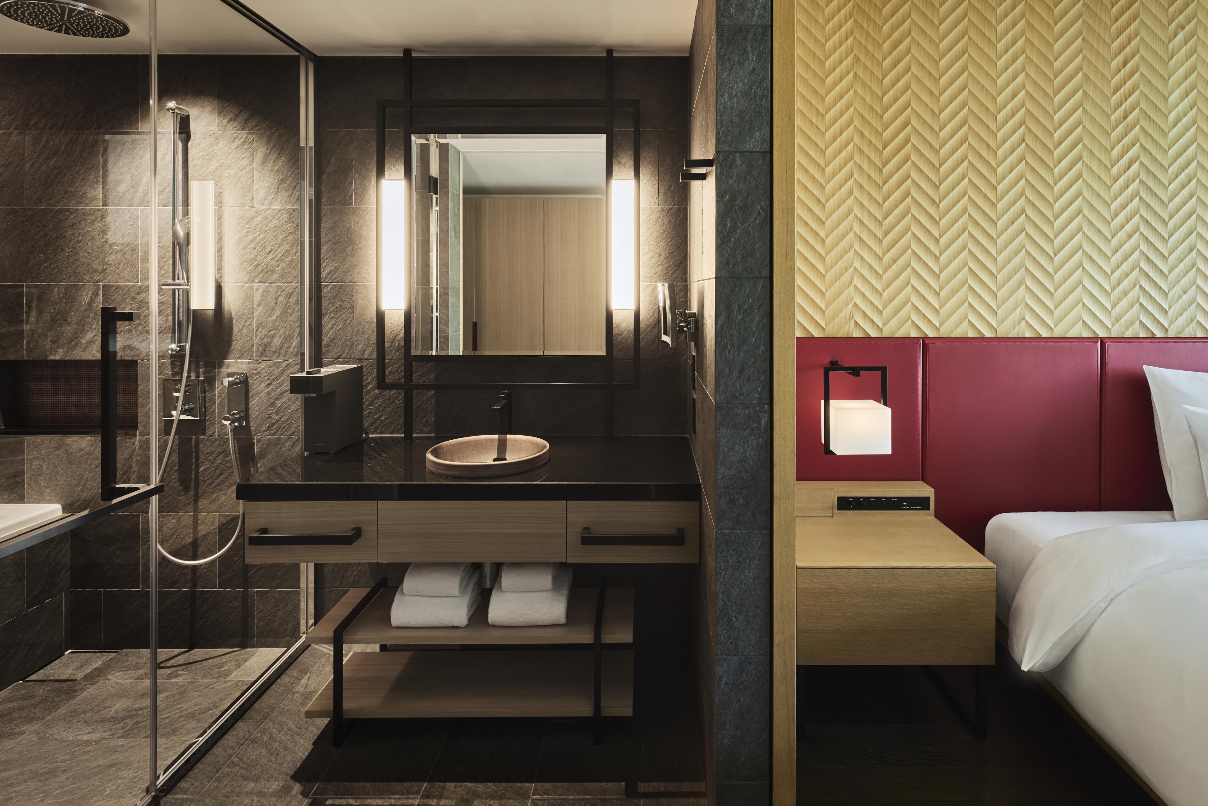 A modern bathroom with a glass-enclosed shower, a wooden vanity, and a large mirror.