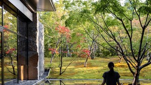 A person meditating in a serene outdoor setting with a view of a garden and a building. - Garrya Nijo Castle Kyoto (Kyoto)