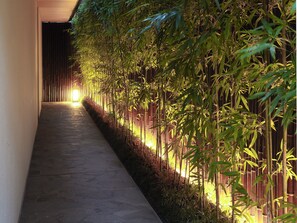 A corridor lined with bamboo plants and illuminated by warm lighting. - Garrya Nijo Castle Kyoto (Kyoto)