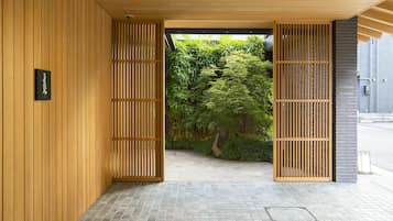 A wooden interior with a sign reading 'Fifty,' a tiled floor, and a view of a lush garden through a wooden screen.