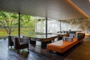 A modern interior with a stone wall, a glass table, and a wooden ceiling. - Garrya Nijo Castle Kyoto (Kyoto)