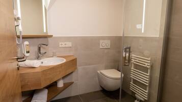 Un bagno moderno con un mobile bagno in legno, un lavandino bianco, un WC e un box doccia in vetro.
