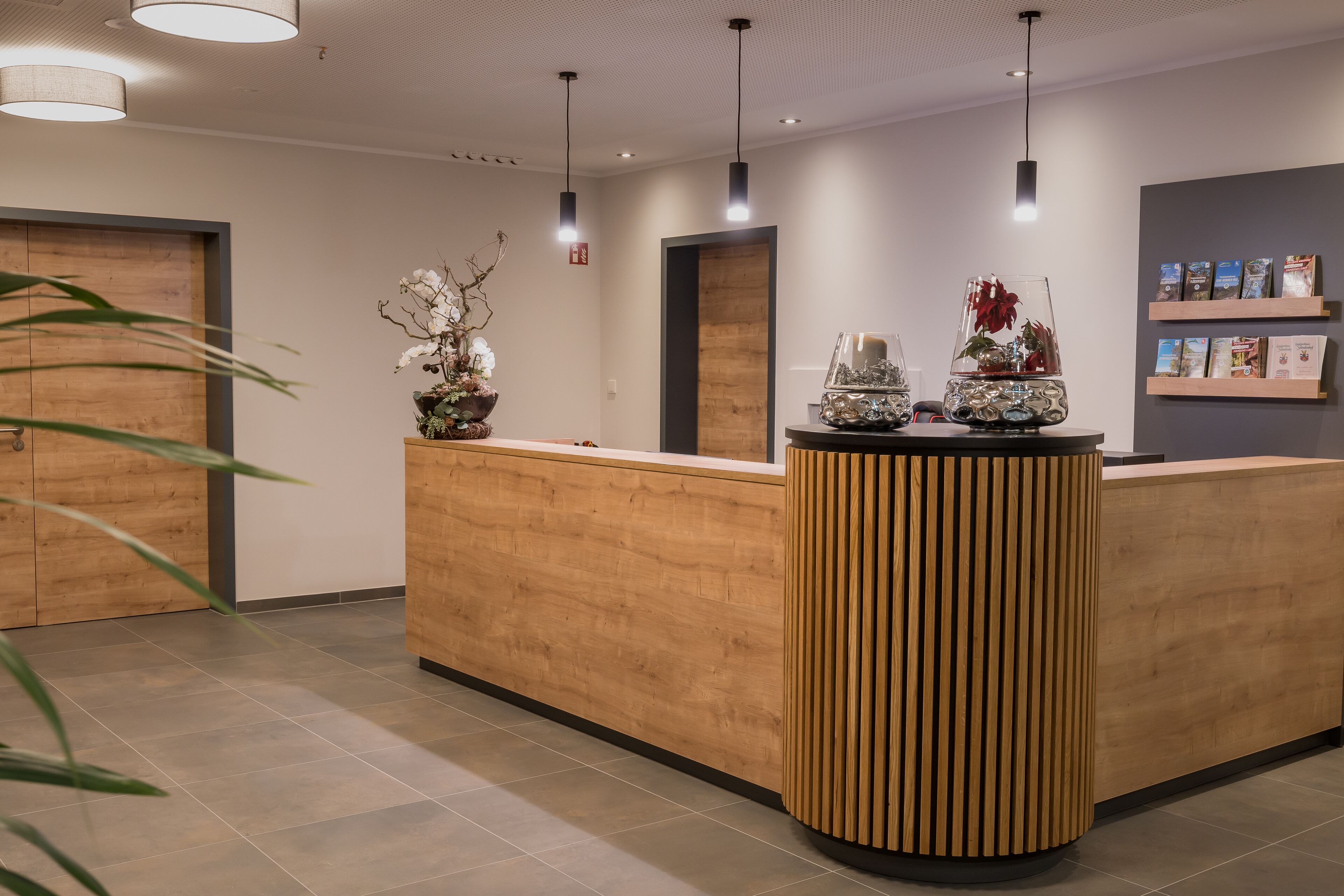 A reception area with a wooden reception desk, pendant lights, and decorative vases.