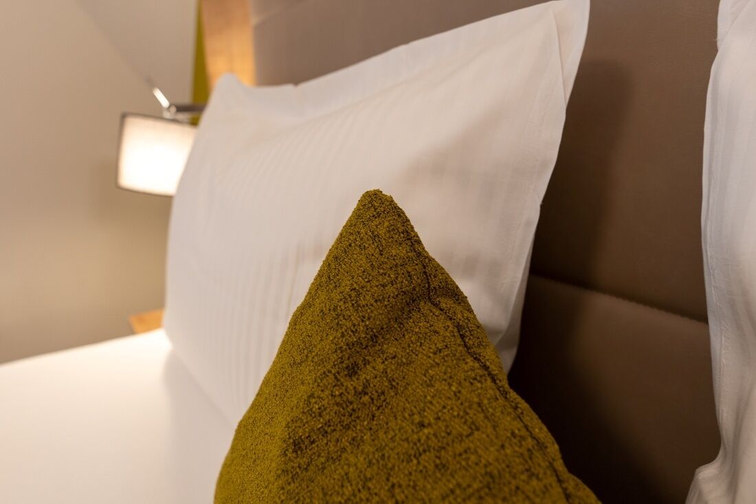 Un lit avec un oreiller blanc et un oreiller vert.