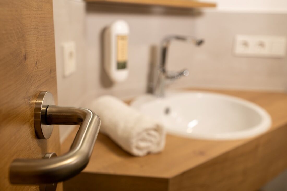 Ein Badezimmer mit einem Holzlaufschrank, einem weißen Waschbecken, einem Handtuch und einem Händetrockner.