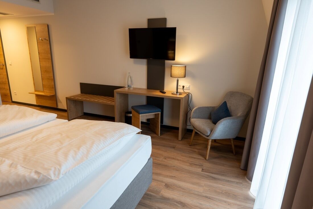 Une chambre d’hôtel comprenant un lit, un bureau avec une chaise, une télévision et une lampe.