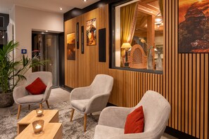 Un hall d’entrée avec deux fauteuils gris, une table basse en bois et une plante en pot.