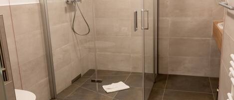 A modern bathroom with a glass-enclosed shower, a toilet, and a vanity with a mirror.