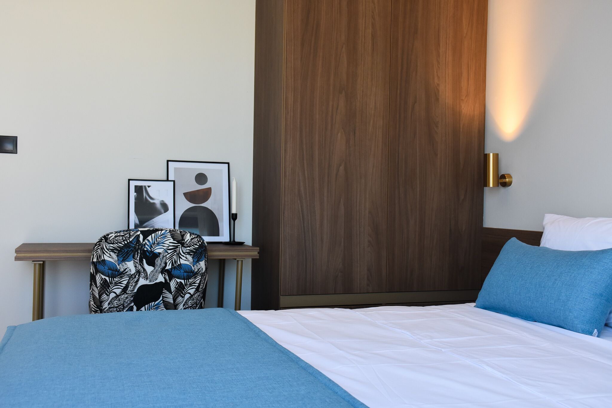 A hotel room with a bed, a nightstand, a chair, and a wardrobe.