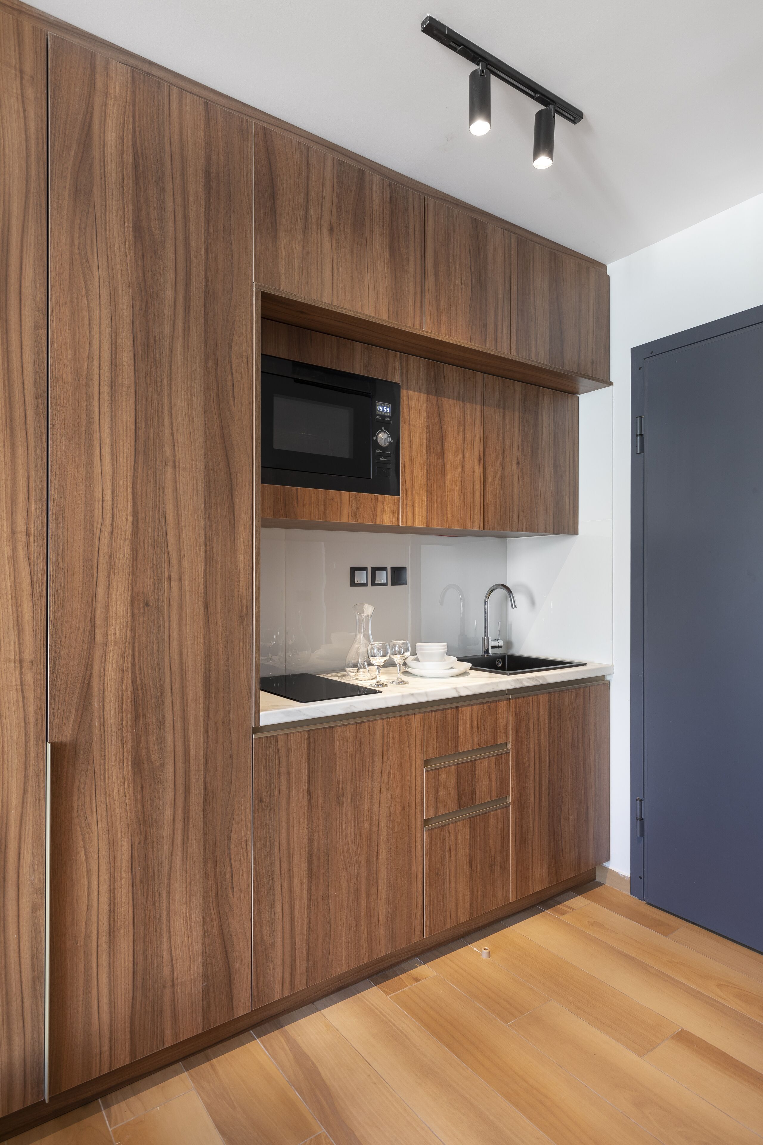 Een moderne keuken met houten kastjes, een magnetron, een spoelbak en een aanrecht.