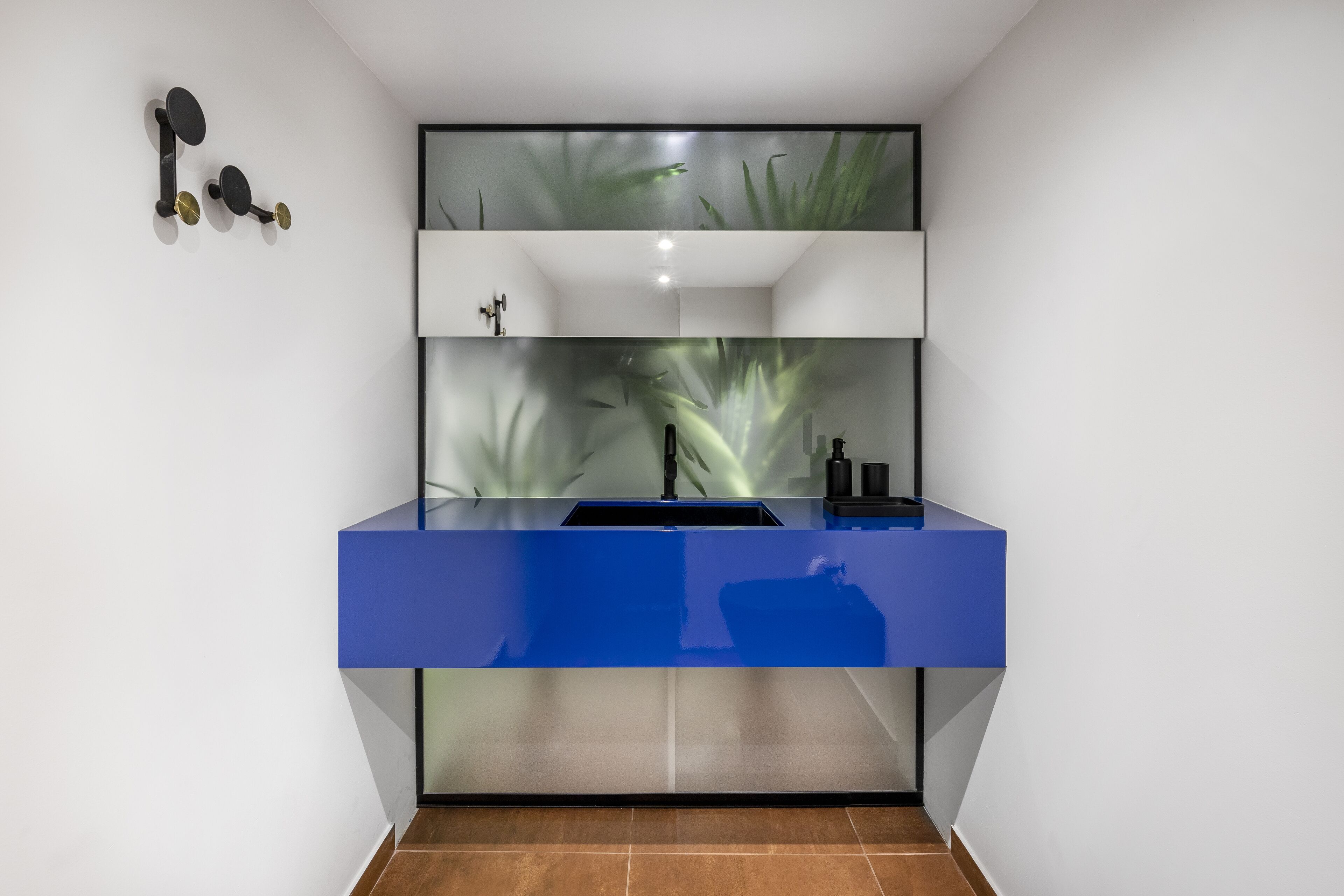 Un baño moderno con un tocador azul, una cabina de ducha con puerta de vidrio y un perchero de toallas en la pared.