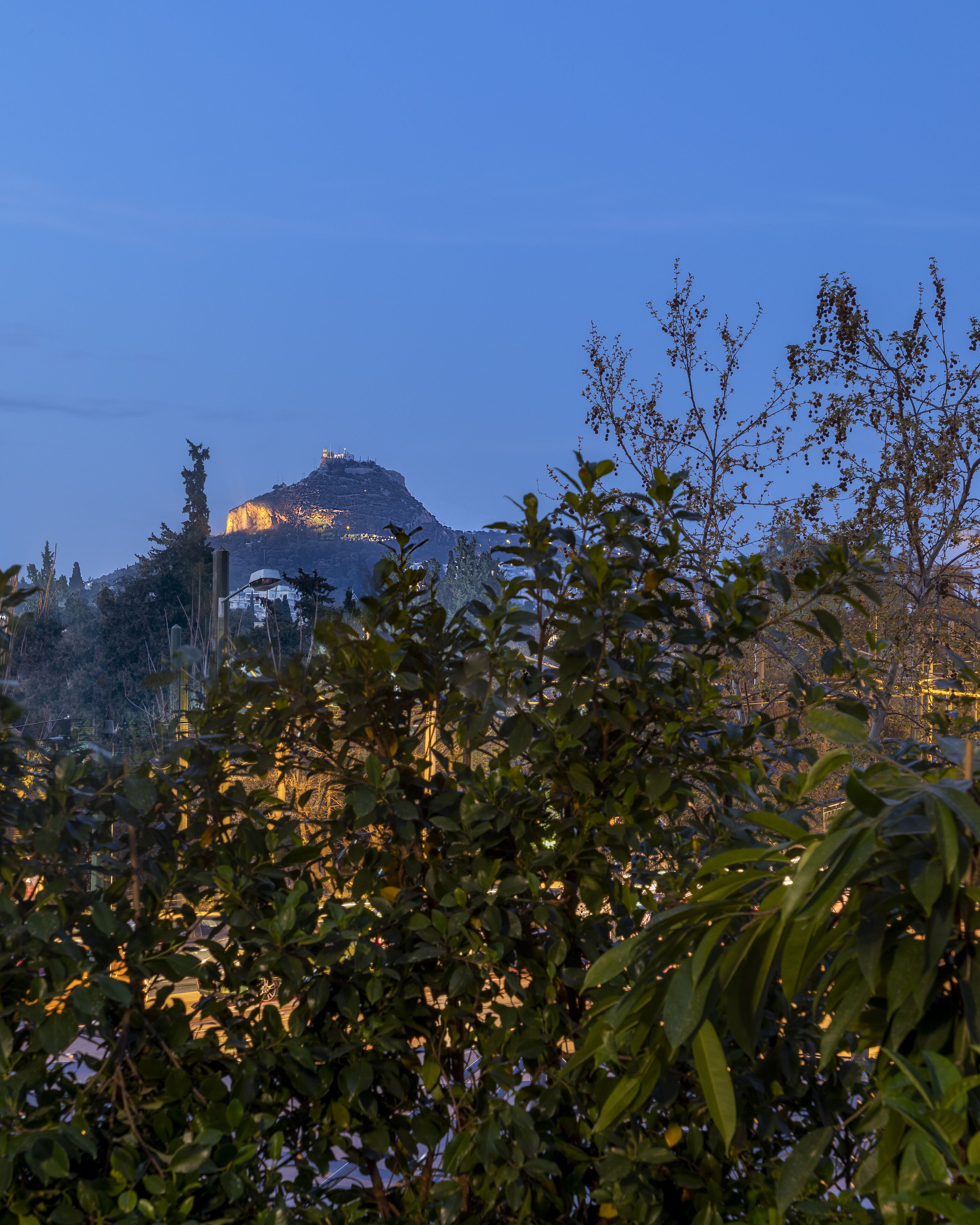A view of a mountain with a building on top, surrounded by trees.