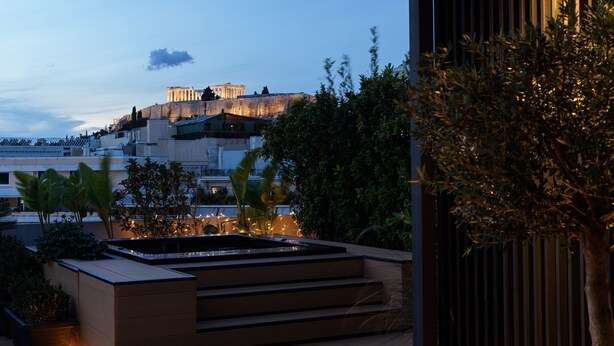 A modern outdoor area with a pool, steps leading to a terrace, and a view of a historic building in the background. - The Newel Acropolis (Athens)