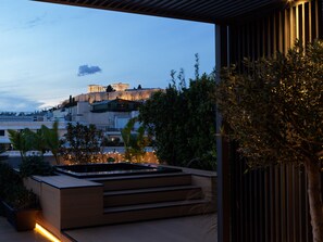 A modern outdoor area with a pool, steps leading to a terrace, and a view of a historic building in the background.