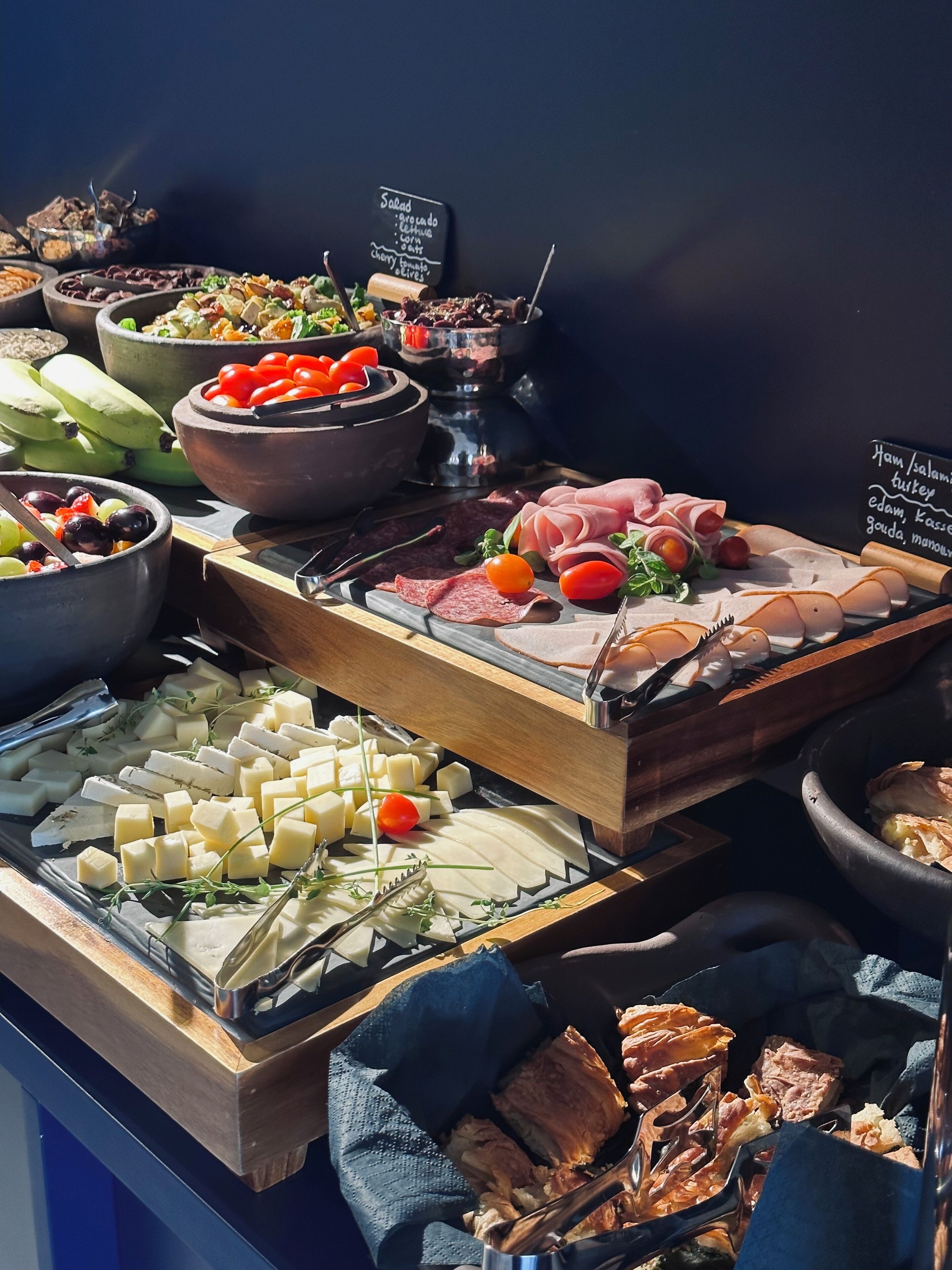 Un bufé con distintos alimentos, incluyendo quesos, carnes y frutas.