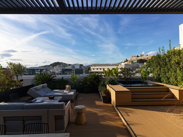 A rooftop terrace with outdoor seating, a hot tub, and a view of the cityscape.