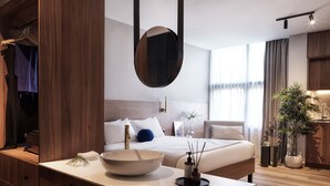 A modern hotel room with a large bed, a bedside table with a bowl, a mirror, and a view of the city through large windows. - The Newel Acropolis (Athens)