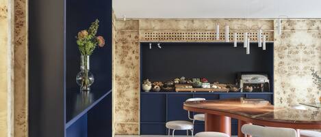 A modern kitchen with a central island, bar stools, and a variety of kitchen appliances.