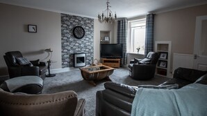 Ein Wohnzimmer mit Steinwand, Fernseher, Kamin und Ledermöbeln.