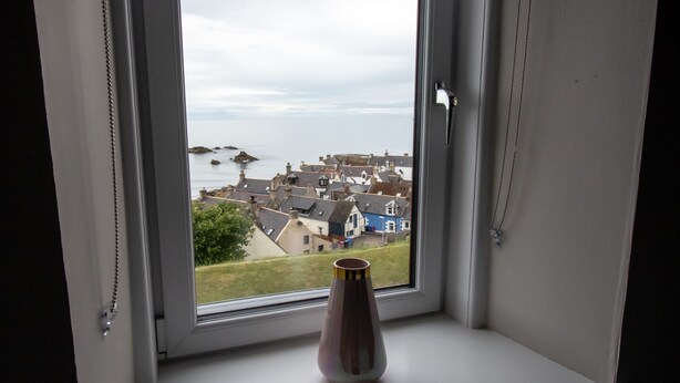 Eine Vase auf einem Fensterbrett mit Blick auf eine Küstenstadt.
