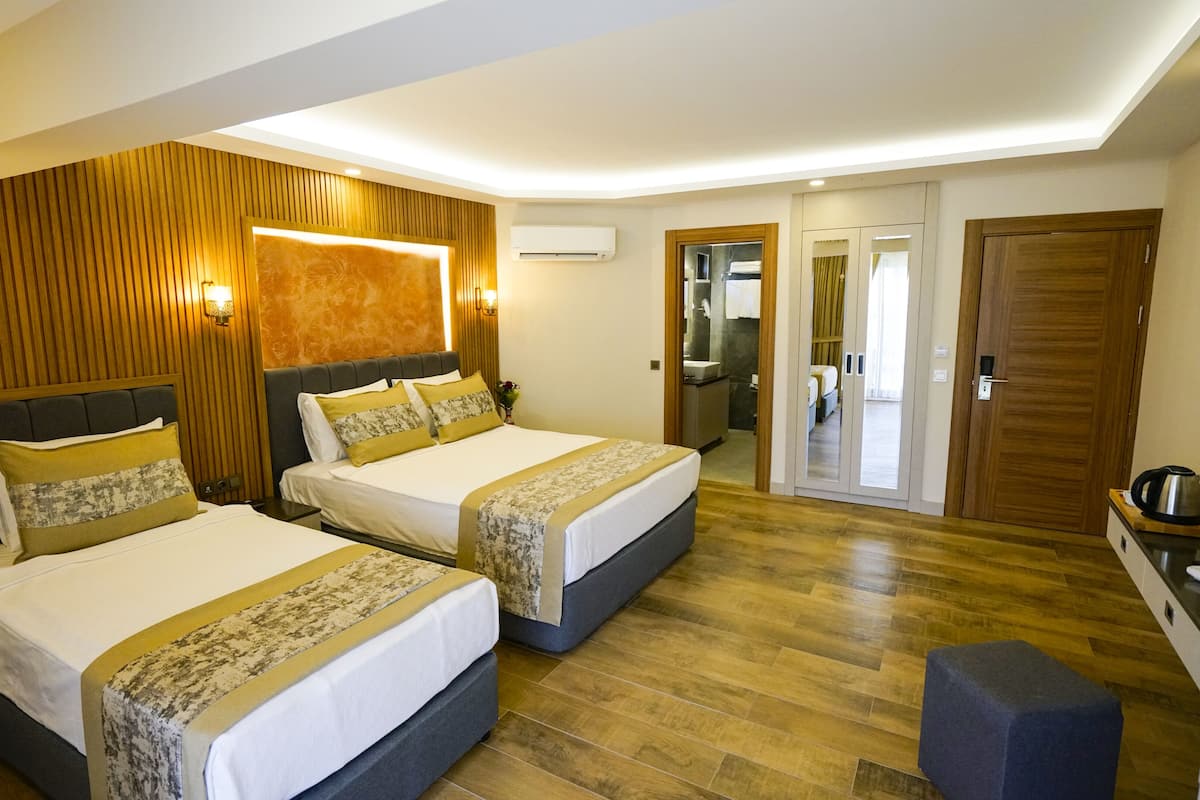 Une chambre d’hôtel avec deux lits, des lambris en bois, un système de climatisation intégré et une kitchenette.