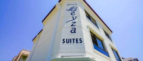 A building with the name "Green Bezza Suites" on its facade.