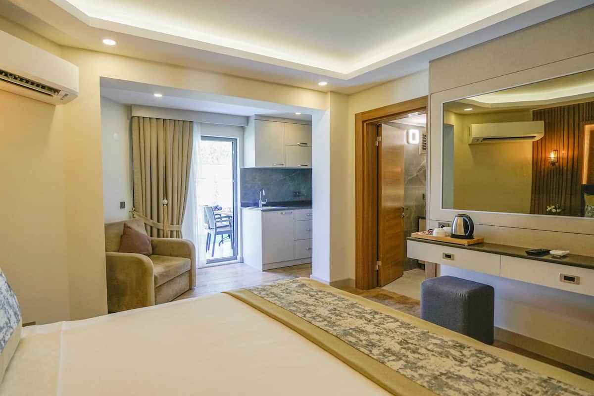Une chambre d’hôtel comprenant un lit, un bureau, une chaise, un coin cuisine et une salle de bain.