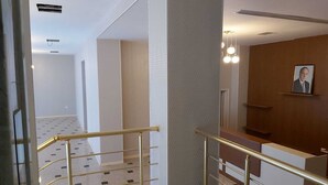 A hotel lobby with a marble floor, a staircase with gold railings, and a wooden reception desk. - Baijan Hotel Baku (Baku)