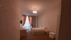A bedroom with a bed, bedside tables, a wardrobe, and a ceiling light fixture. - Baijan Hotel Baku (Baku)