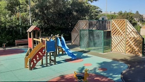 Un’area giochi con uno scivolo, strutture per arrampicata e un campo da basket.